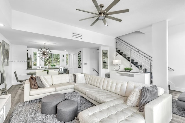 living room with sink, ceiling fan with notable chandelier, and light wood-type flooring