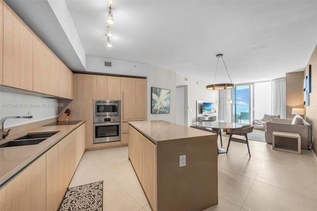 kitchen featuring sink, light brown cabinets, appliances with stainless steel finishes, a kitchen island, and pendant lighting