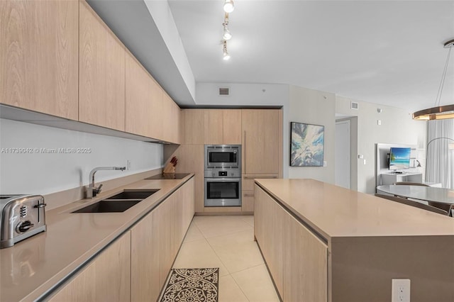 kitchen featuring sink, a kitchen island, light brown cabinets, and appliances with stainless steel finishes