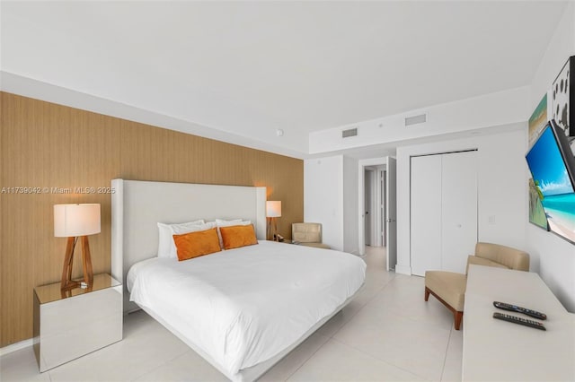 bedroom featuring wooden walls, a closet, and light tile patterned floors