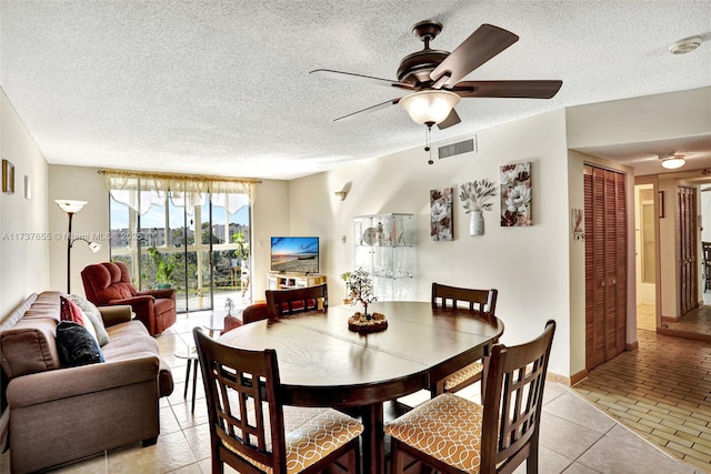 tiled dining area featuring ceiling fan and a textured ceiling