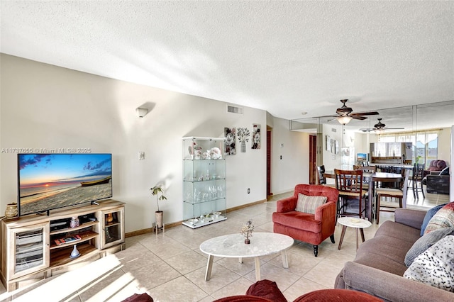 living room featuring light tile patterned flooring, ceiling fan, and a textured ceiling