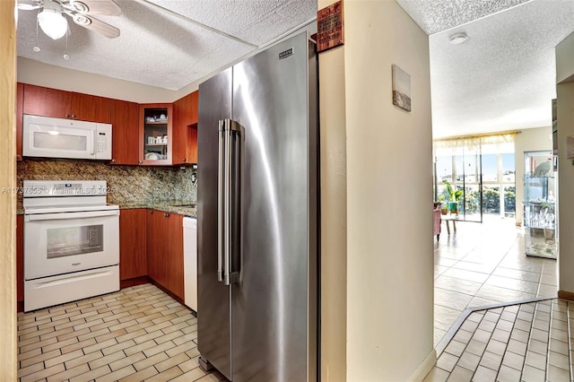 kitchen with backsplash, white appliances, ceiling fan, light stone countertops, and a textured ceiling