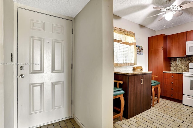 kitchen with ceiling fan, white appliances, a textured ceiling, and backsplash