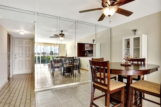 tiled dining room with ceiling fan and a textured ceiling