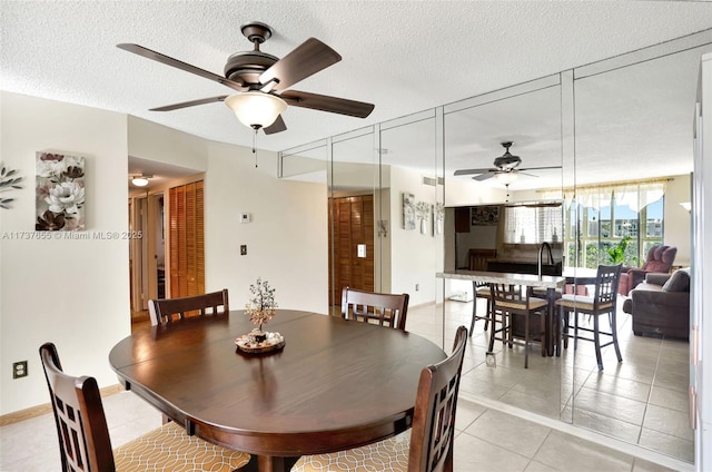 tiled dining room with ceiling fan and a textured ceiling