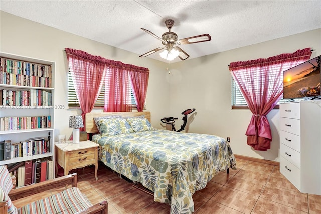 tiled bedroom featuring ceiling fan and a textured ceiling