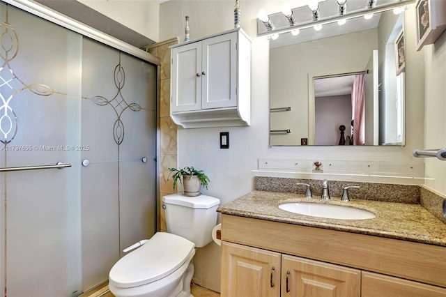 bathroom featuring vanity, an enclosed shower, and toilet