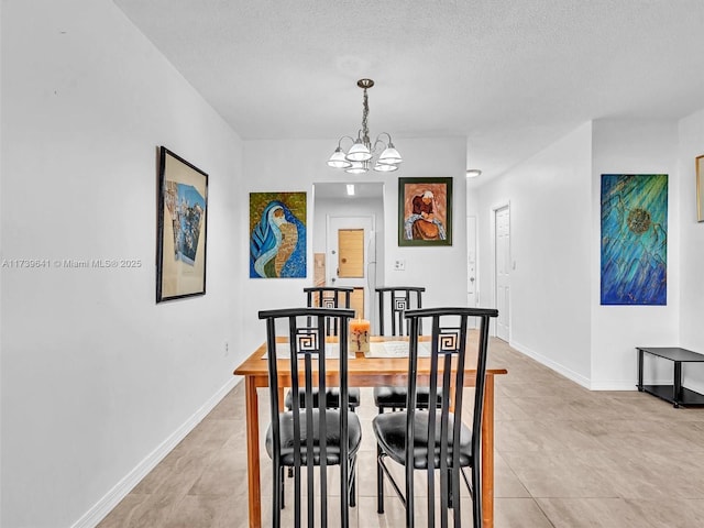 dining area with a textured ceiling, baseboards, and a notable chandelier