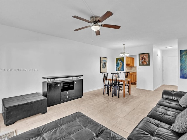 living area with light tile patterned floors, ceiling fan with notable chandelier, and baseboards