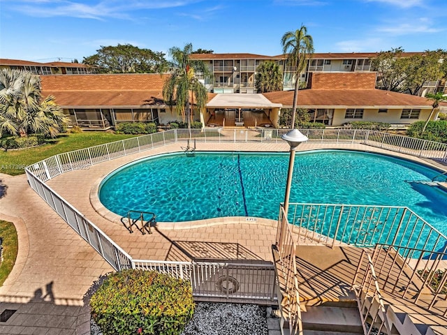 pool with a residential view, a patio area, and fence