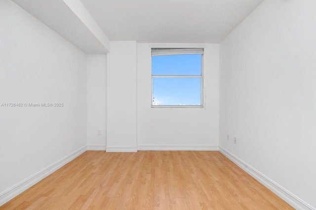 spare room featuring a textured ceiling and light hardwood / wood-style floors