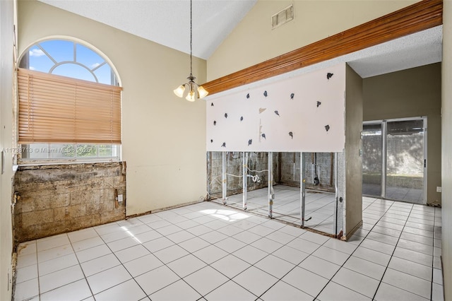 unfurnished room with light tile patterned floors, a textured ceiling, high vaulted ceiling, and a chandelier