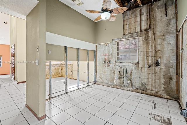 spare room featuring light tile patterned flooring, ceiling fan, and a high ceiling