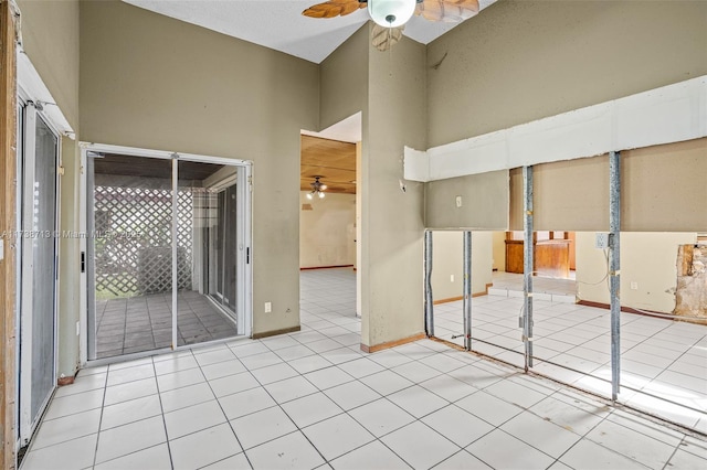 empty room featuring a towering ceiling, ceiling fan, and light tile patterned flooring