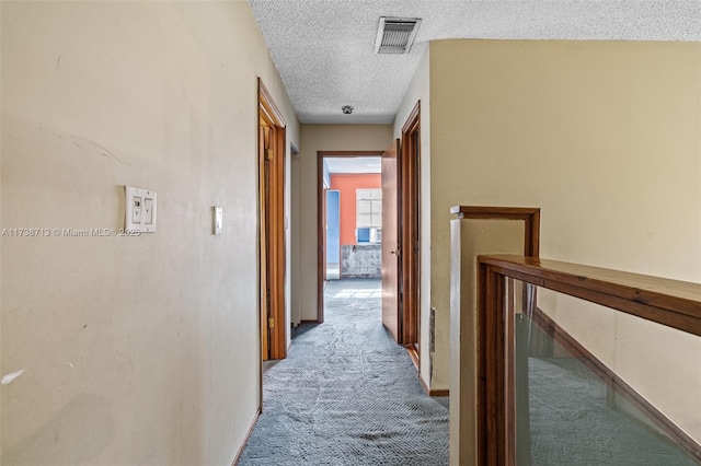 corridor with light colored carpet and a textured ceiling