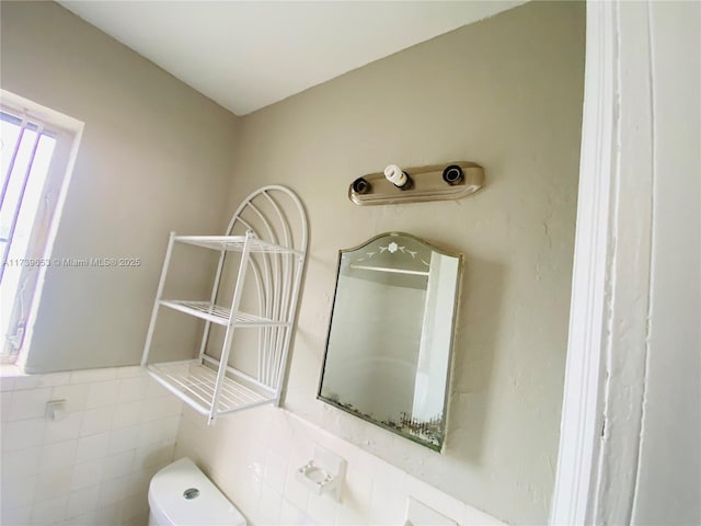 bathroom featuring tile walls and toilet