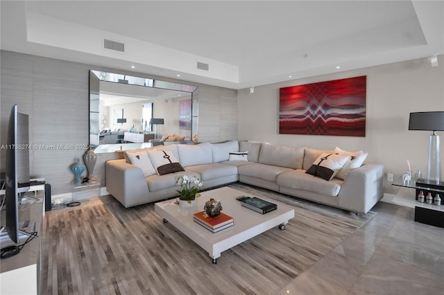 living room with visible vents, a raised ceiling, and recessed lighting