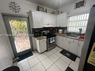 kitchen with white cabinetry, light tile patterned flooring, and stainless steel electric range oven