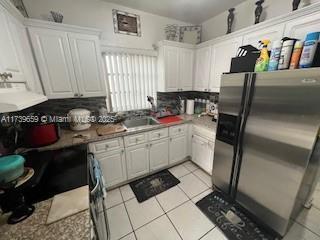 kitchen featuring white cabinets, light tile patterned flooring, sink, and stainless steel fridge