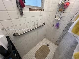 bathroom featuring tiled shower and tile walls