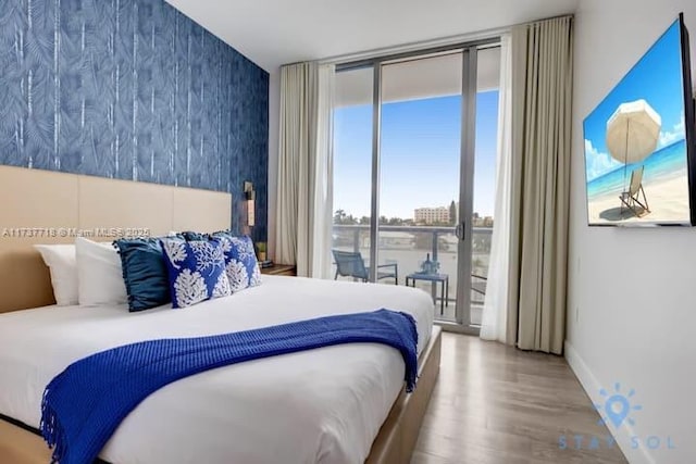 bedroom featuring expansive windows, hardwood / wood-style floors, and access to exterior