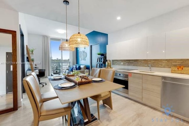 kitchen with pendant lighting, sink, appliances with stainless steel finishes, tasteful backsplash, and white cabinets