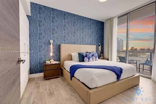 bedroom featuring light hardwood / wood-style flooring, access to outside, and floor to ceiling windows