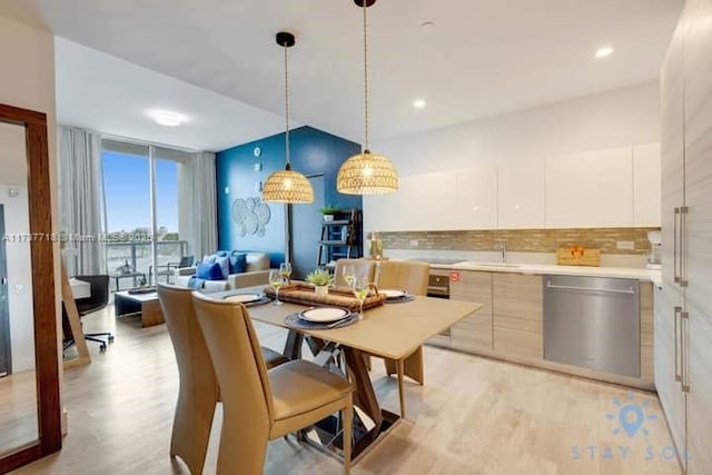 kitchen with pendant lighting, light hardwood / wood-style flooring, dishwasher, white cabinetry, and backsplash