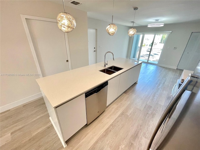 kitchen featuring sink, white cabinetry, decorative light fixtures, stainless steel dishwasher, and an island with sink