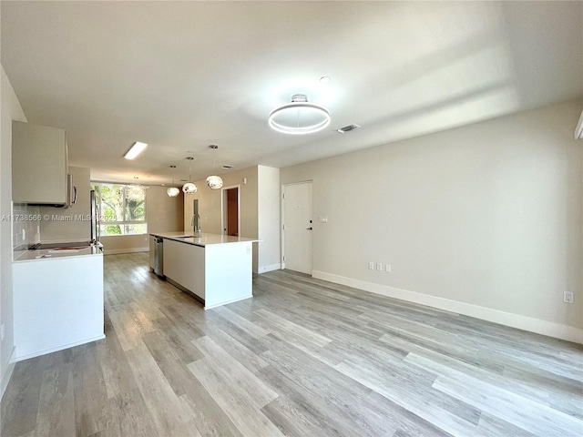 kitchen with pendant lighting, dishwasher, sink, a kitchen island with sink, and light hardwood / wood-style flooring