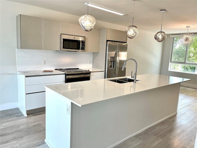 kitchen featuring a kitchen island with sink, decorative light fixtures, tasteful backsplash, and stainless steel appliances