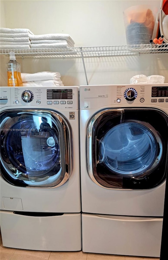 washroom featuring light tile patterned flooring and washing machine and clothes dryer