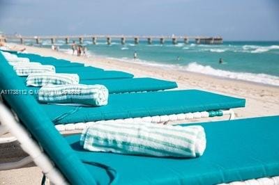 view of pool with a water view and a beach view