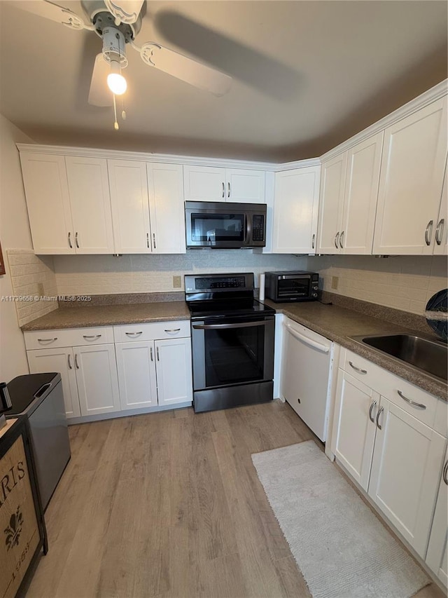 kitchen with stainless steel appliances, white cabinetry, tasteful backsplash, and light wood-type flooring