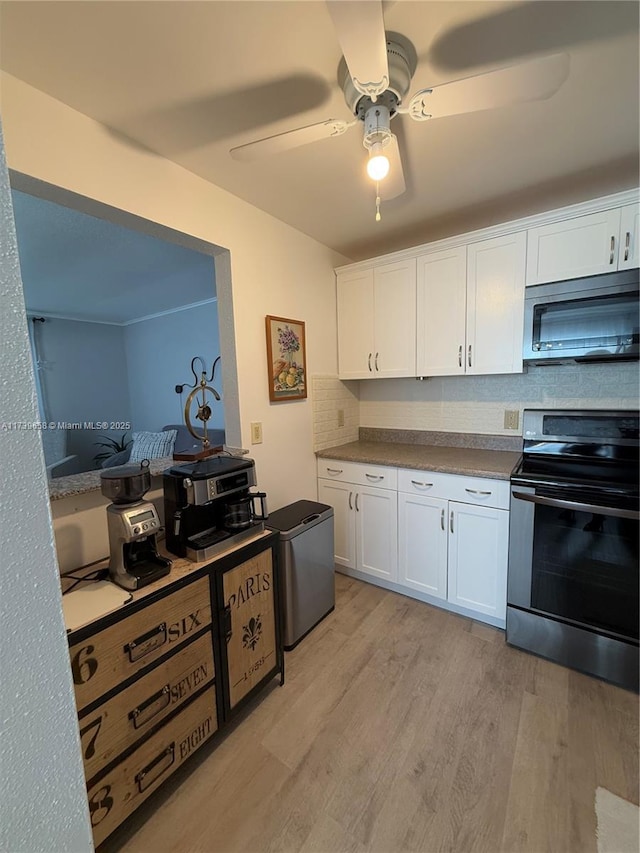 kitchen featuring light hardwood / wood-style flooring, appliances with stainless steel finishes, white cabinets, ceiling fan, and backsplash