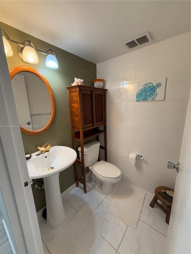 bathroom featuring tile walls and toilet