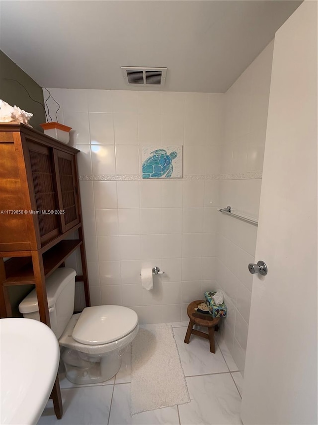 bathroom with sink, tile walls, and toilet