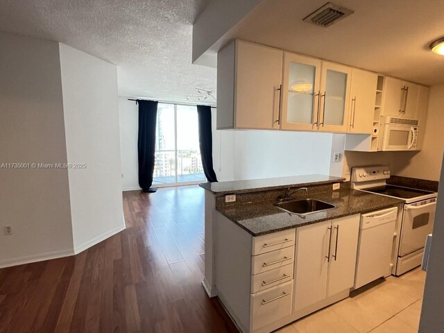 kitchen featuring sink, dark stone countertops, white appliances, and light wood-type flooring