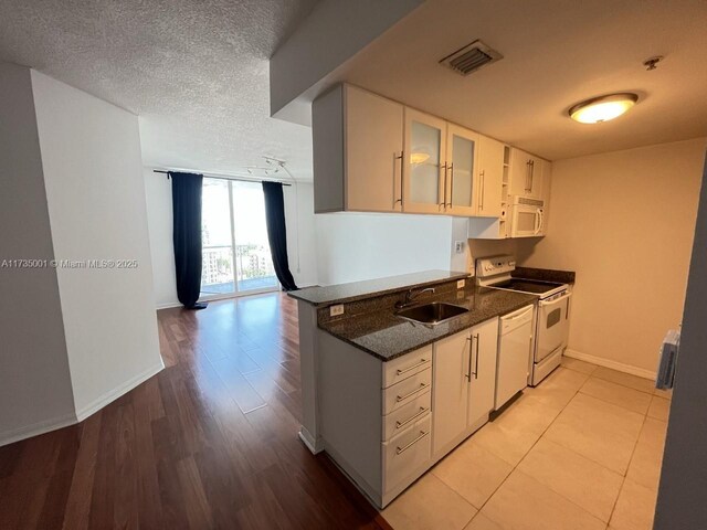 kitchen featuring water heater, sink, white appliances, and light hardwood / wood-style floors