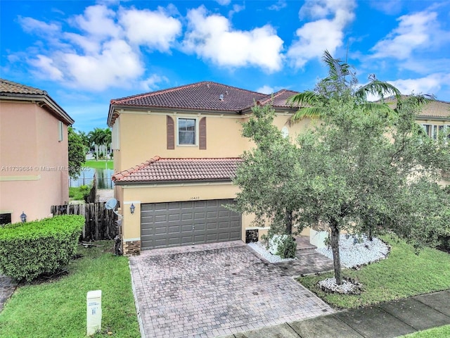 mediterranean / spanish house with a garage, a water view, and a front lawn