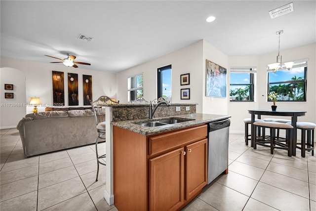 kitchen featuring sink, hanging light fixtures, light tile patterned floors, dishwasher, and a kitchen island with sink