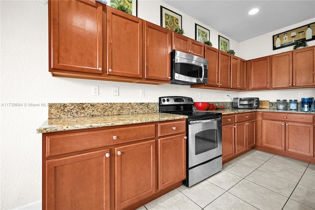 kitchen with light tile patterned flooring, light stone countertops, and appliances with stainless steel finishes