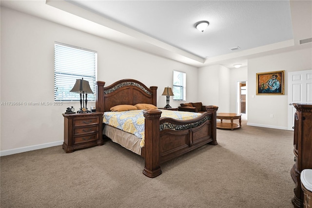 bedroom featuring light carpet and a tray ceiling