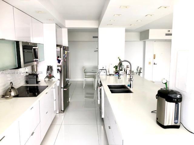 kitchen with light tile patterned floors, appliances with stainless steel finishes, sink, and white cabinets