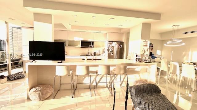kitchen featuring stainless steel appliances, white cabinets, a kitchen bar, hanging light fixtures, and light countertops