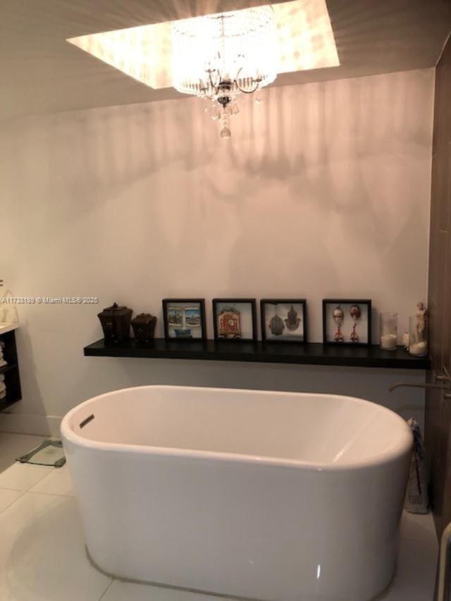 full bath featuring a chandelier, a freestanding tub, and tile patterned flooring