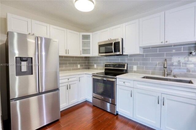 kitchen with dark wood-type flooring, sink, white cabinetry, appliances with stainless steel finishes, and decorative backsplash