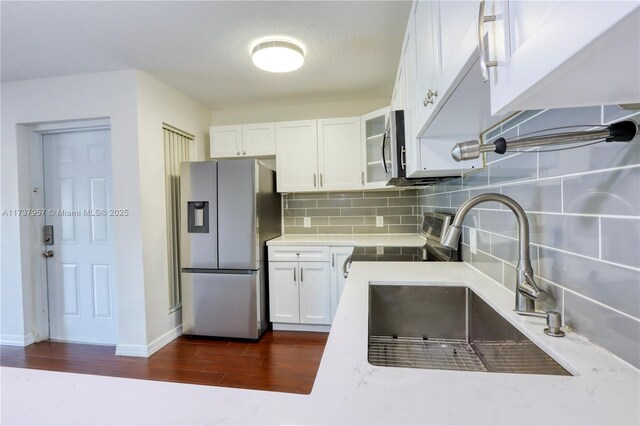 kitchen featuring sink, white cabinetry, dark hardwood / wood-style flooring, stainless steel appliances, and decorative backsplash