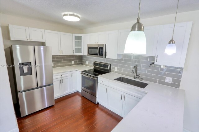 kitchen with sink, appliances with stainless steel finishes, white cabinetry, decorative backsplash, and decorative light fixtures